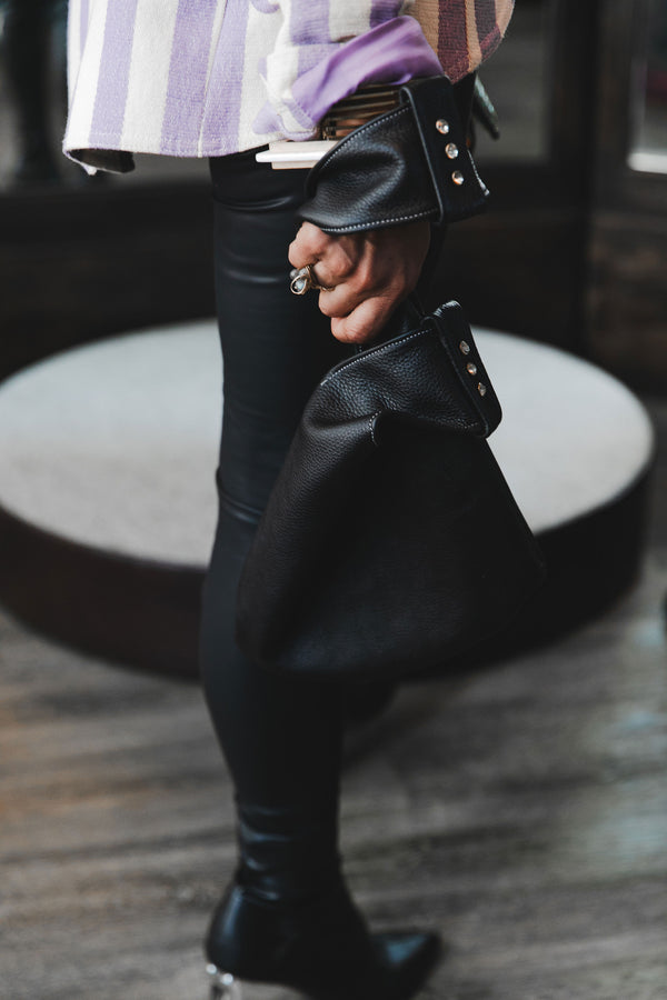Photo of a woman wearing the No Rehearsalco Vivi Bag in black leather. 